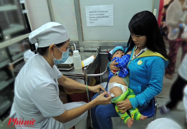 Người dân đưa con trẻ đến chích ngừa vắc xin tại Trung tâm Y tế Dự phòng TP.HCM.