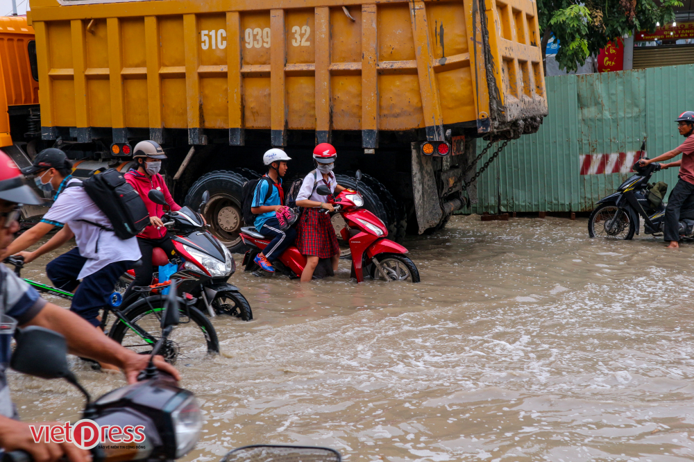 Các em học sinh khó khăn trong việc di chuyển giữa mênh mông nước trên đường Huỳnh Tấn Phát, nơi chỉ cách điểm kiểm soát Phú Xuân đang bị ngưng trệ khoảng 100m.