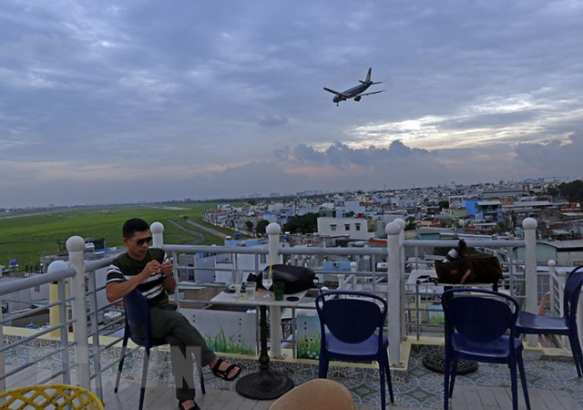  Phần lớn giới trẻ tại các quận gần khu vực sân bay Tân Sơn Nhất thường xuyên ngồi xem máy bay trên quán càphê sân thượng. (Ảnh: Huy Hùng/TTXVN)