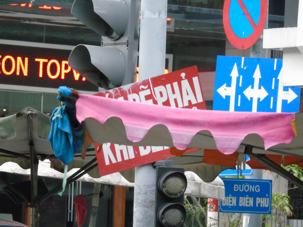 Biển báo cho phép rẽ phải khi đèn đỏ bị ô dù từ các sạp hàng rong trên đường Nguyễn Thượng Hiền (Q.3) che khuất.