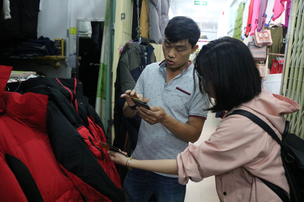 Anh Trần Huy Thu một tiểu thương tại chợ đang tư vấn cho khách hàng lựa chọn. (Ảnh: Huy Hoàng)