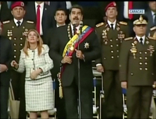 Ông Maduro và các quan chức đang đứng kế bên ngước nhìn lên không trung vài giây trước khi bài phát biểu bị ngắt dừng. Ảnh: Reuters