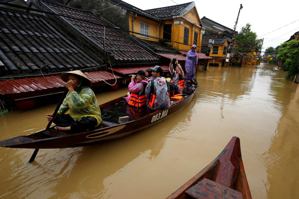 Người dân chèo thuyền trên đường phố Hội An, khu vực nước lũ dâng cao đến mái nhà. Ảnh: Reuters