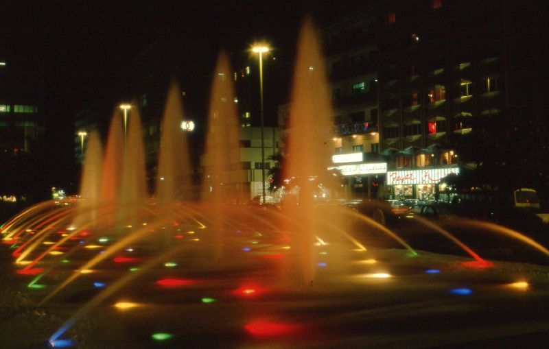 Vòi phun nước tráng lệ với hệ thống đèn chiếu sáng tại một quảng trường.