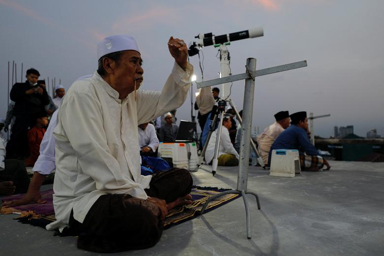 Ishak Sholeh, một người đàn ông Hồi giáo 66 tuổi, tìm kiếm vị trí của mặt trăng trên mái thờ Hồi giáo Al-Musyari\'in để đánh dấu ngày đầu tiên của tháng Ramadan, Jakarta, Indonesia.