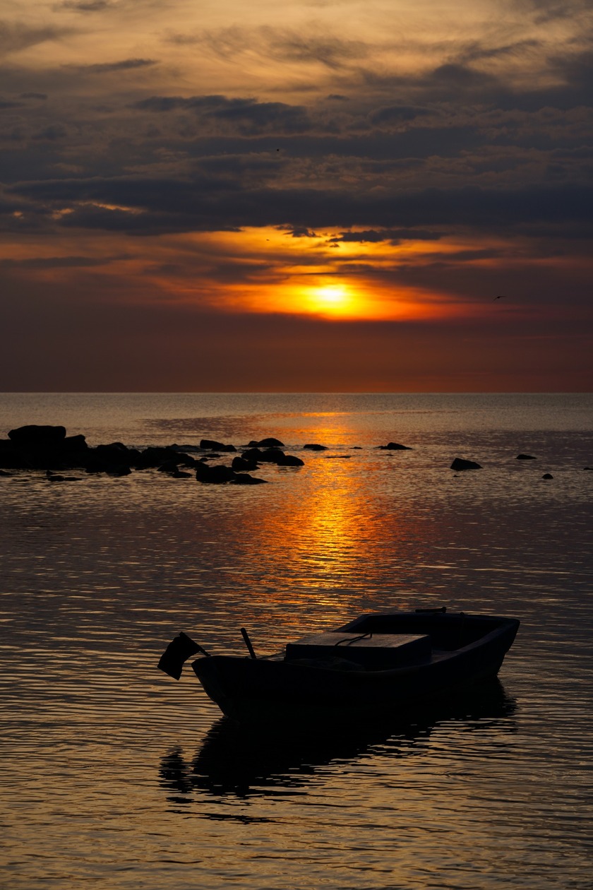 Đứng trên bãi biển ngắm nhìn những con thuyền đang nhấp nhô ngoài khơi xa vào khoảnh khắc mặt trời ló rạng.