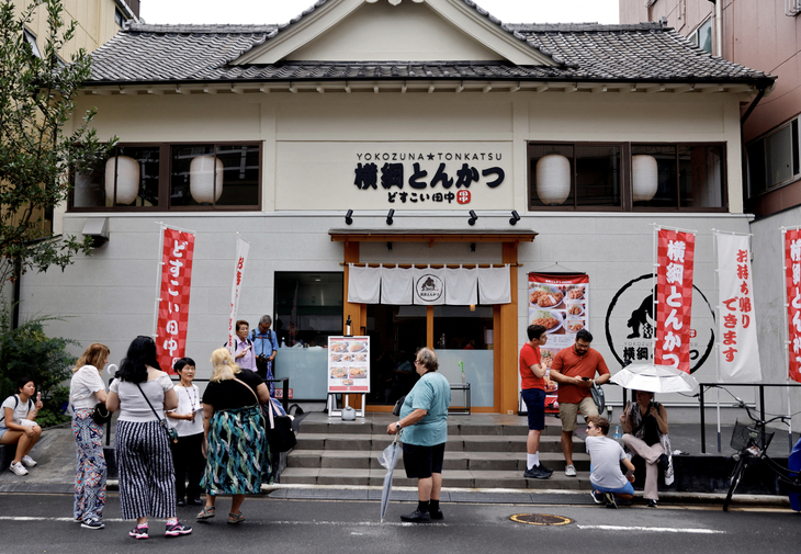 Khách du lịch nước ngoài chờ đợi bên ngoài nhà hàng nổi tiếng lấy chủ đề về sumo có tên Yokozuna Tonkatsu Dosukoi Tanaka (Nhật Bản) vào ngày 30-6-2023 - Ảnh: REUTERS