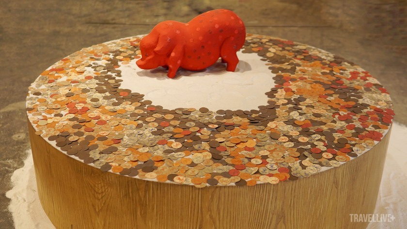Bách Nguyễn mang đến tác phẩm Nuôi lợn gầy, với hình ảnh chú lợn sơn đỏ, vây quanh bởi những đồng tiền xu bằng giấy