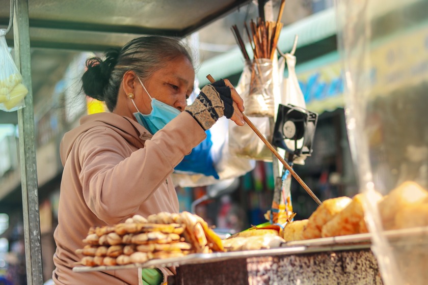 Đôi tay bà thoăn thoắt trở bề từng trái chuối sao cho lớp da trở nên vàng nâu