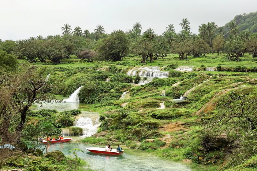 Khách du lịch ngồi trên thuyền tại thác nước Wadi Darbat, nơi đóng vai trò như một ốc đảo cho du khách có thể khám phá khí hậu mát mẻ và cảnh quan xanh tươi của thành phố, tại tỉnh Dhofar, Oman