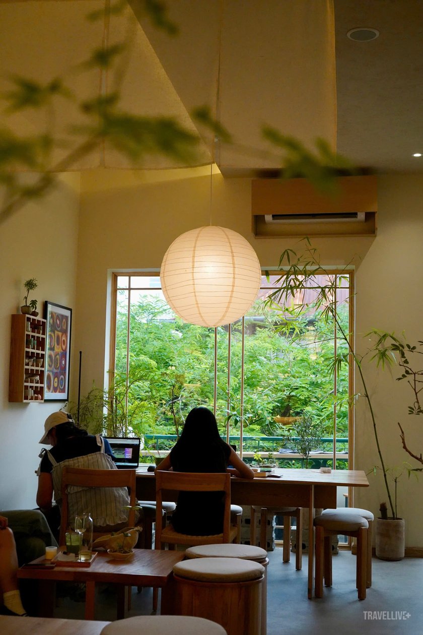 Một góc bàn nhỏ cạnh cửa sổ, nơi lý tưởng để ngắm mưa qua vòm me xanh