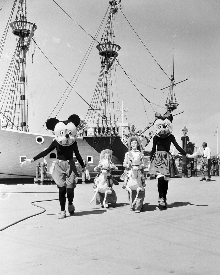 Biểu tượng của Disney, chuột Mickey và Minnie, đi cùng trẻ em gần một con tàu cướp biển trong ngày khai trương Disneyland