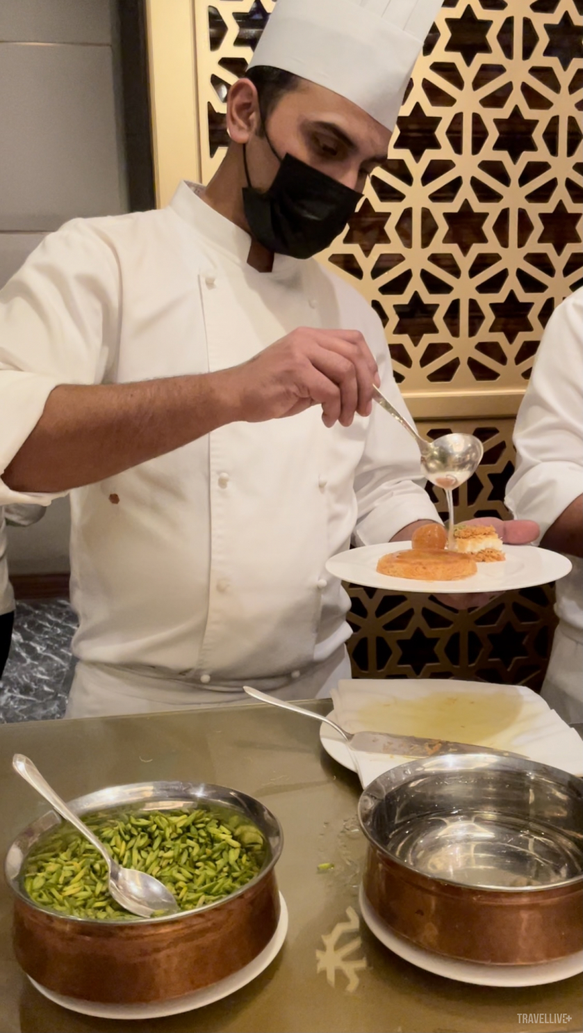 Nghệ nhân hoàn thành món kunafa bằng lớp siro đặc biệt và rắc lên trên cùng một ít pitaschio.