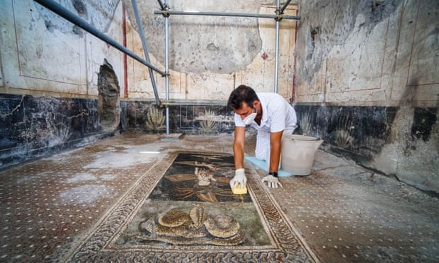 Một công nhân đang lau chùi bức tranh khảm trên sàn tại dinh thự Casa di Orione gần cửa hàng Thermopolium mới được khai quật, dinh thự này cũng sẽ mở cửa công khai trong tương lai. Ảnh: Cesare Abbate/EPA