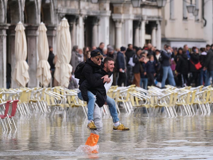 Dễ dàng bắt gặp cảnh mọi người cõng nhau lội nước - Ảnh: Reuters/Manuel Silvestri