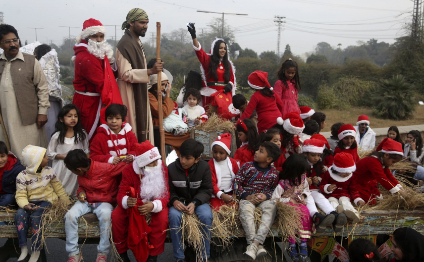 Các tín đồ Cơ đốc giáo hóa trang thành ông già Noel, vây quanh diễn cảnh Chúa giáng sinh trong một cuộc diễu hành tại Lahore, Pakistan - Ảnh: KM Chaudary/AP