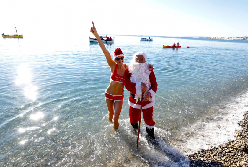 Một người đàn ông hoá trang thành ông già Noel tạo dáng với một vận động viên bơi lội, trong buổi tắm chung Giáng Sinh thường niên tại Promenade des Anglais, dọc đường bờ biển ở Nice, Pháp - Ảnh: Eric Gaillard/Reuters