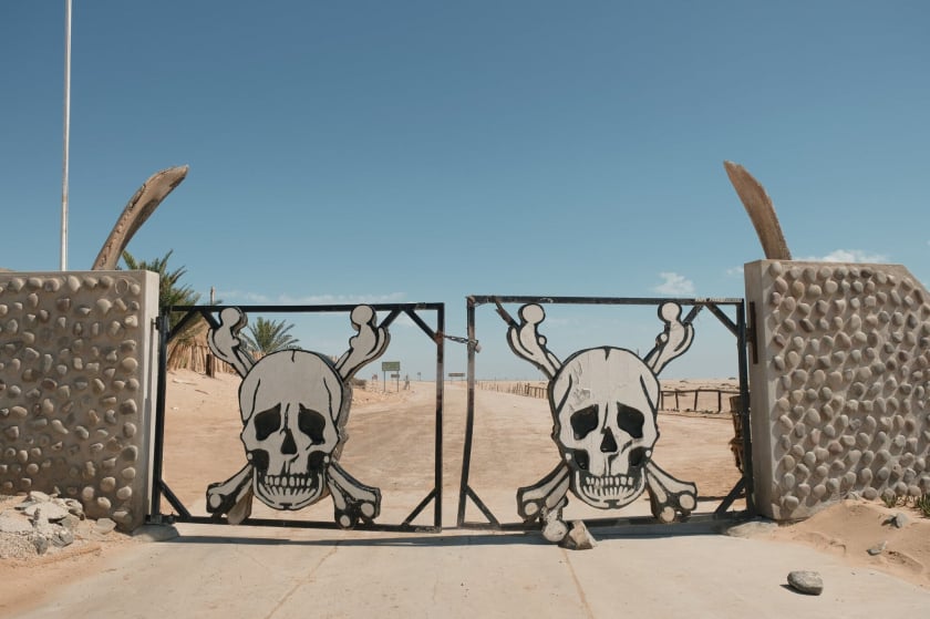 Cổng Ugab, lối vào phía nam của bờ biển Skeleton, với hình ảnh trang trí để cảnh báo về những nguy hiểm và điều kiện khắc nghiệt đang chờ đợi du khách ở phía bên kia.