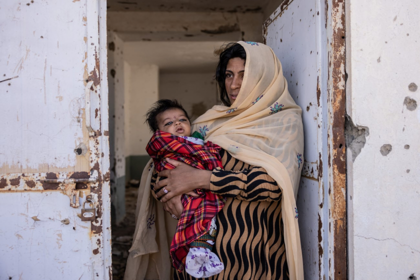 Nakiba (30 tuổi) bế cậu con trai Mustafa 2 tháng tuổi, trước khung cửa nơi từng là một phòng khám ở thị trấn Sangin, nay đã bị phá huỷ bởi bom đạn.