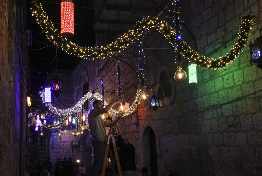 Jerusalem, Israel. Một người đàn ông Palestine treo đèn trang trí để chuẩn bị cho tháng lễ Ramadan - Ảnh: Mahmoud Illean/AP