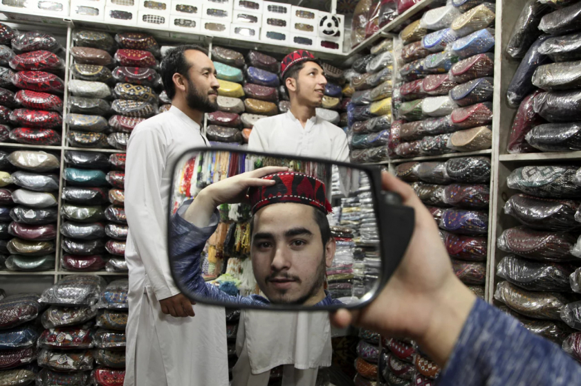   Peshawar, Pakistan. Một chàng trai đang ướm thử chiếc mũ truyền thống trong lúc mua đồ chuẩn bị cho tháng Ramadan - Ảnh: Muhammad Sajjad/AP