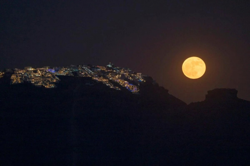 Hình ảnh trăng dâu tây mọc sau làng Imerovigli nằm ở miệng núi lửa Santorini, trên quần đảo Cyclades, Hy Lạp