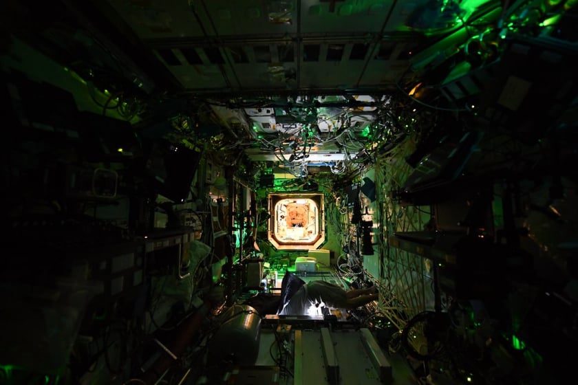 Đèn LED màu xanh lá cây chiếu sáng mô-đun phòng thí nghiệm của Hoa Kỳ bên trong ISS, trong khi ánh sáng mặt trời phản chiếu từ Trái đất chiếu lên trần nhà