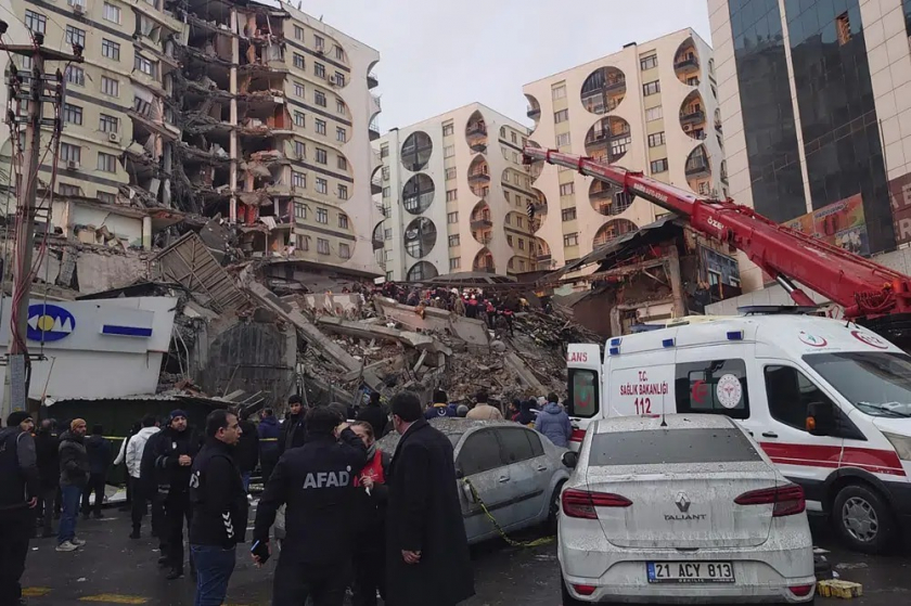Lực lượng cứu hộ sử dụng cần cẩu để tìm kiếm nạn nhân mắc kẹt dưới đống đổ nát sau động đất tại Diyarbakir, trong khi nhân viên y tế túc trực, sẵn sàng đưa người bị thương đến bệnh viện