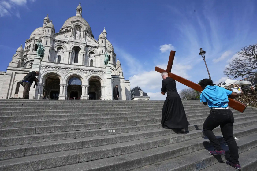 Cha xứ đang mang thập giá trên vai trong buổi Lễ Phục Sinh tại Pháp - Ảnh: Michel Euler/AP.