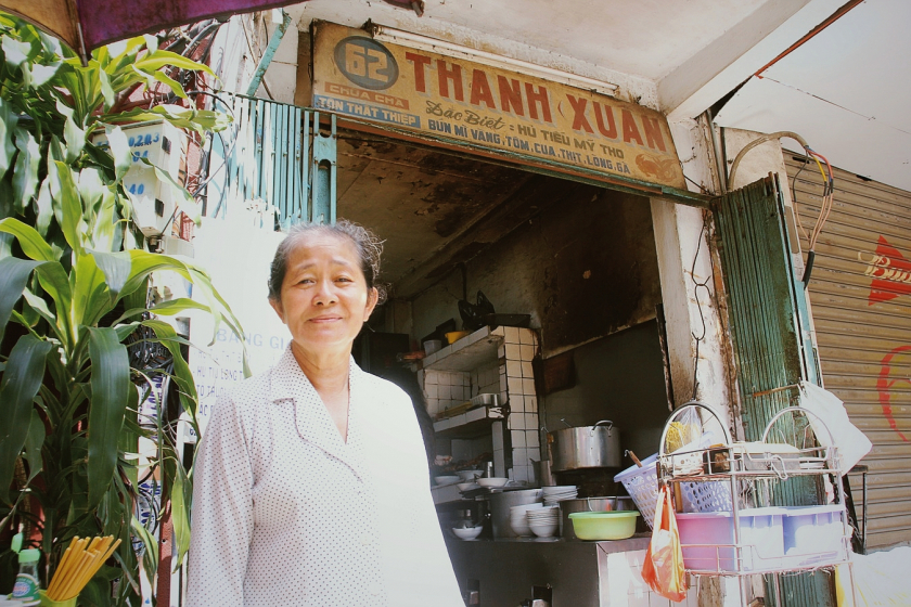 Bà Võ Thị Tươi bên tiệm hủ tiếu với bảng hiệu viết tay truyền thống