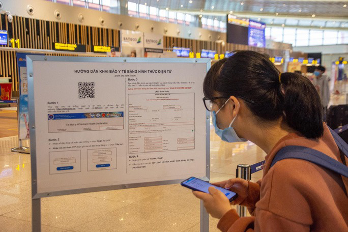 Hành khách xem hướng dẫn khai báo y tế tại sân bay Vân Đồn - Ảnh: NLĐ