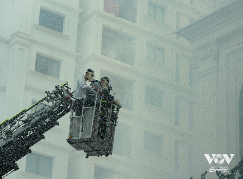 Người dân bị mắc kẹt trên tầng cao được lực lượng chức năng dùng xe thang để giải cứu, trên mặt có đeo mặt nạ để chống khí độc xâm nhập vào cơ thể.