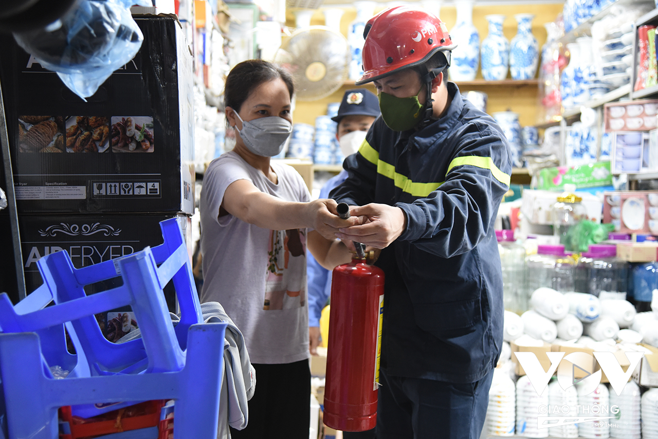 Cảnh sát PCCC&CNCH huyện Hoài Đức hướng dẫn các hộ kinh doanh sử dụng bình chữa cháy.