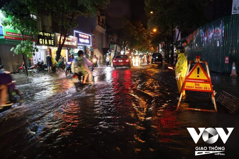 Trên phố Lạc Trung, quận Hai Bà Trưng, một số điểm có nguy cơ ngập sâu, công nhân của Công ty TNHHH MTV Thoát nước Hà Nội phải túc trực để cảnh báo cho người đi đường, đồng thời khơi thông miệng thoát để lưu thoát nước nhanh hơn