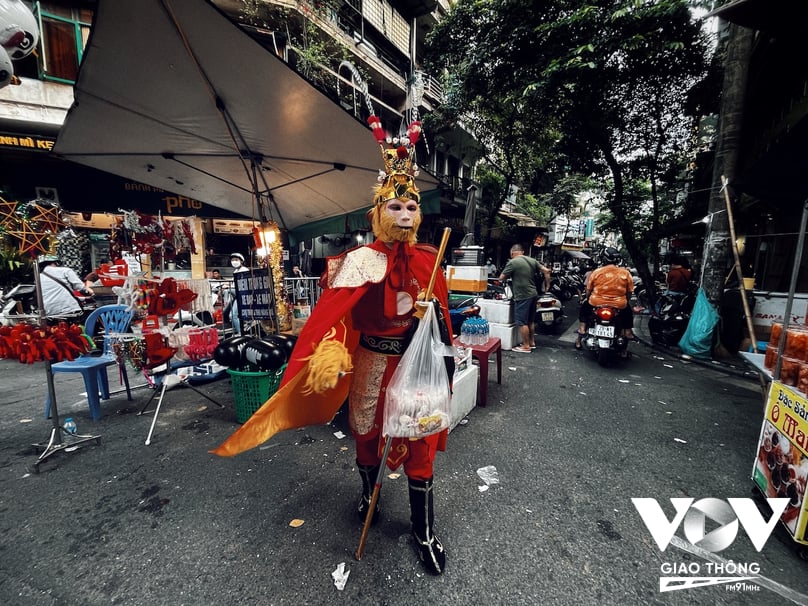 Một người bán hàng mặc bộ quần áo và hoá trang thành Tôn Ngộ Không trên phố Hàng Mã