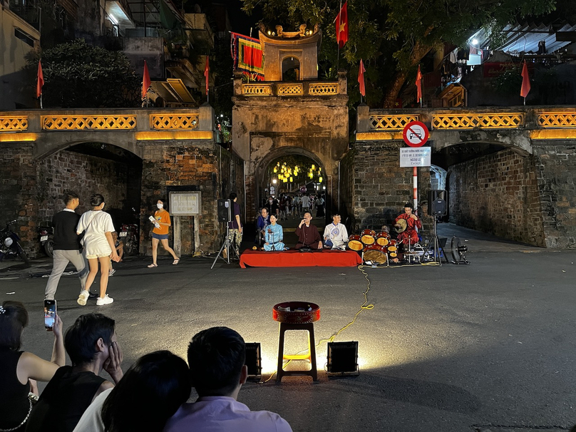Khách du lịch ngồi thưởng thức nghệ thuật truyền thống bên cổng Ô Quan Chưởng đêm Trung thu