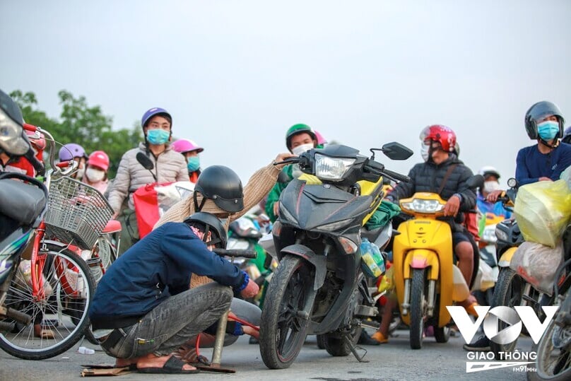 Trong lúc chờ khai báo y tế để tiếp tục lên đường, một số người dân tranh thủ kiểm tra lốp xe.