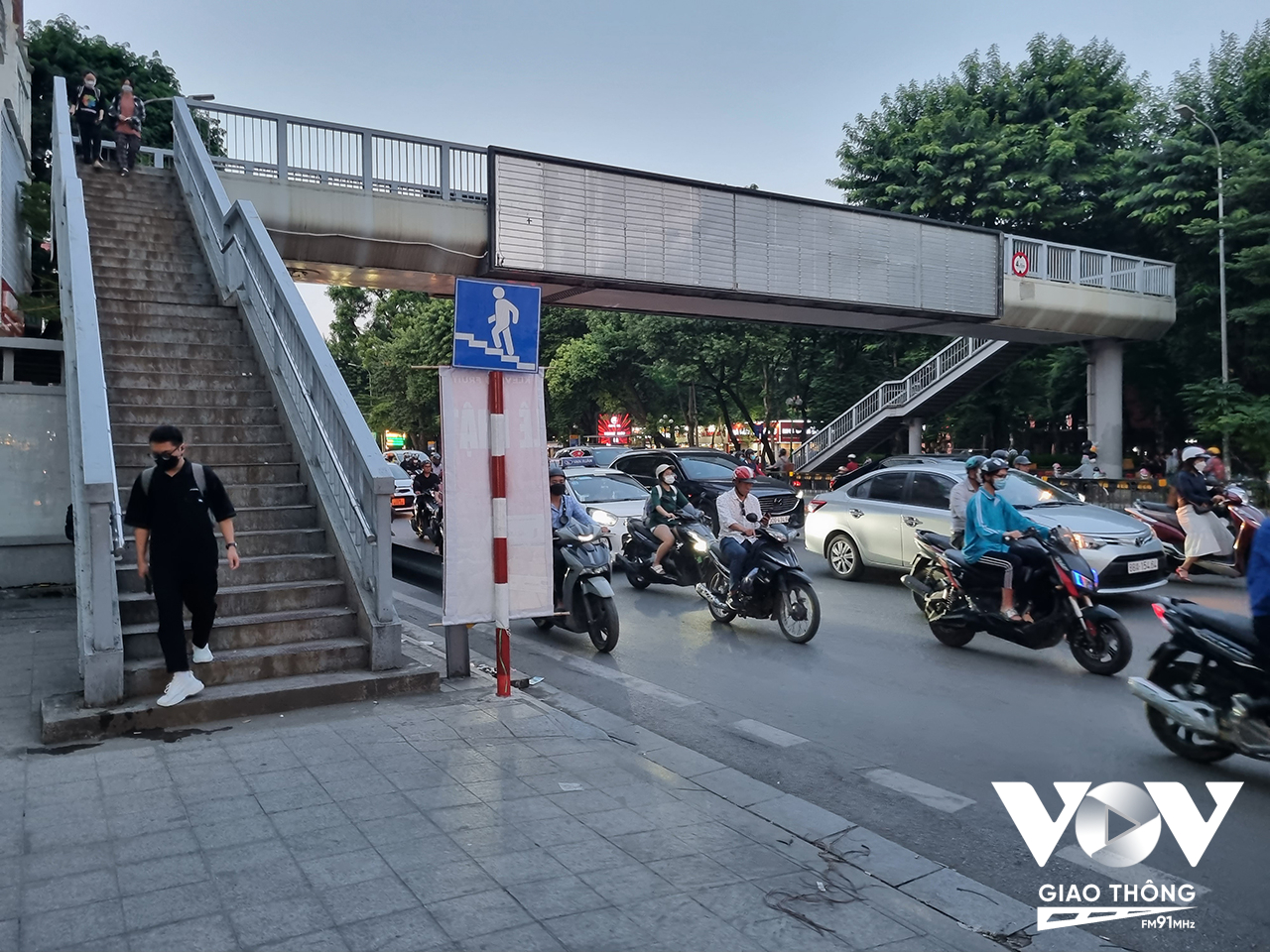 Hàng rào trên dải phân cách và dòng xe đông đúc buộc người đi bộ sử dụng cầu bộ hành, hạn chế tình trạng sang đường tùy tiện. Hình ảnh ghi nhận trên phố Tây Sơn.