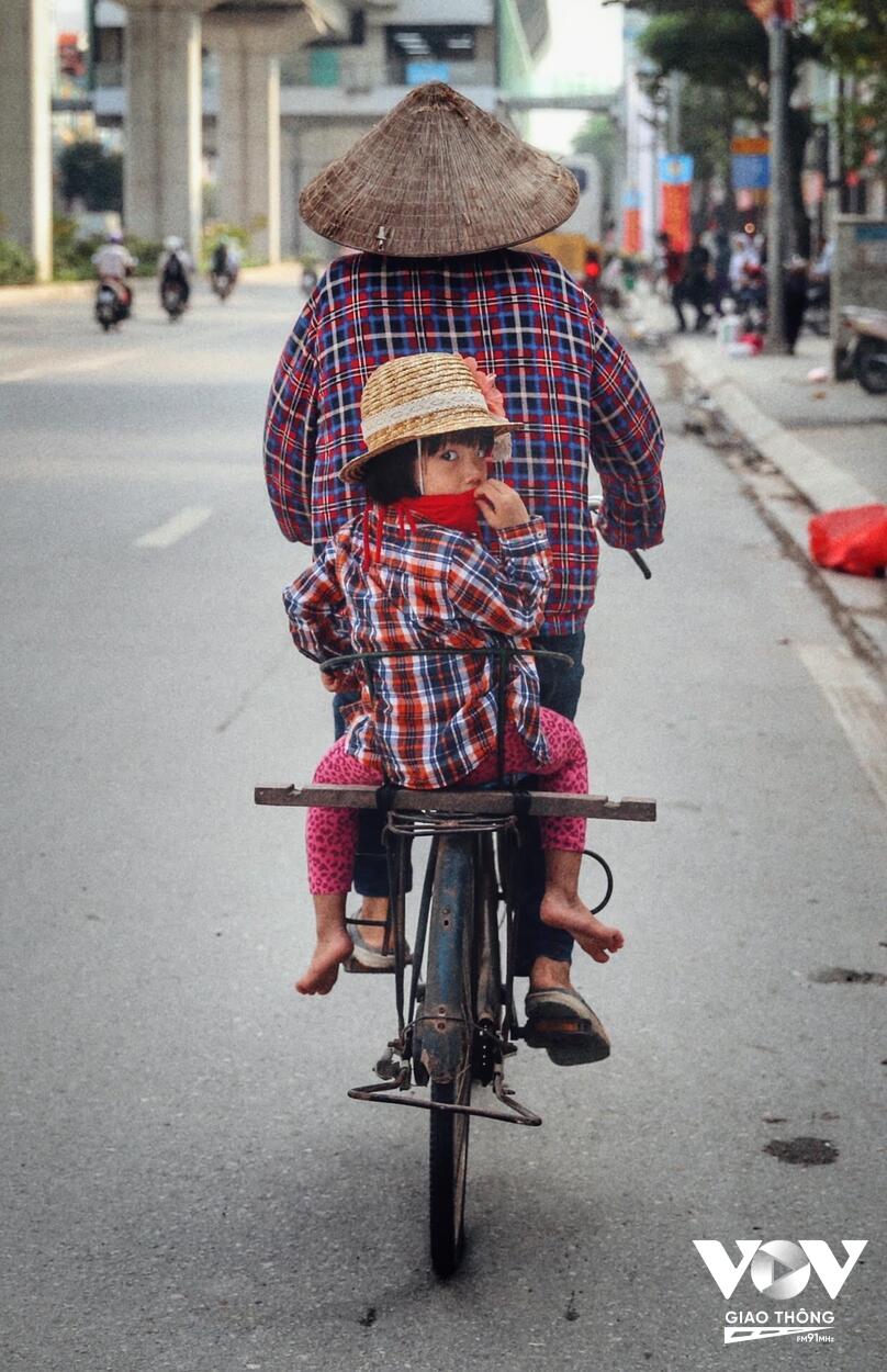Người mẹ chở con gái trên chiếc xe đạp trên đường đi làm