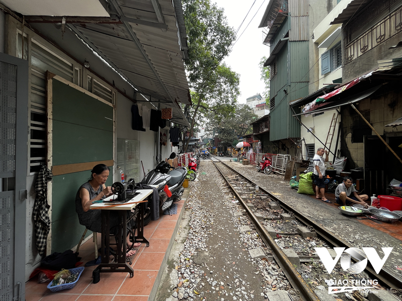 Cụ bà ngồi may quần áo bên chiếc máy khâu cũ trên phố đường tàu Phùng Hưng
