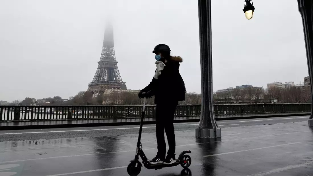 Một phụ nữ lái scooter gần Eiffel - Ảnh AFP