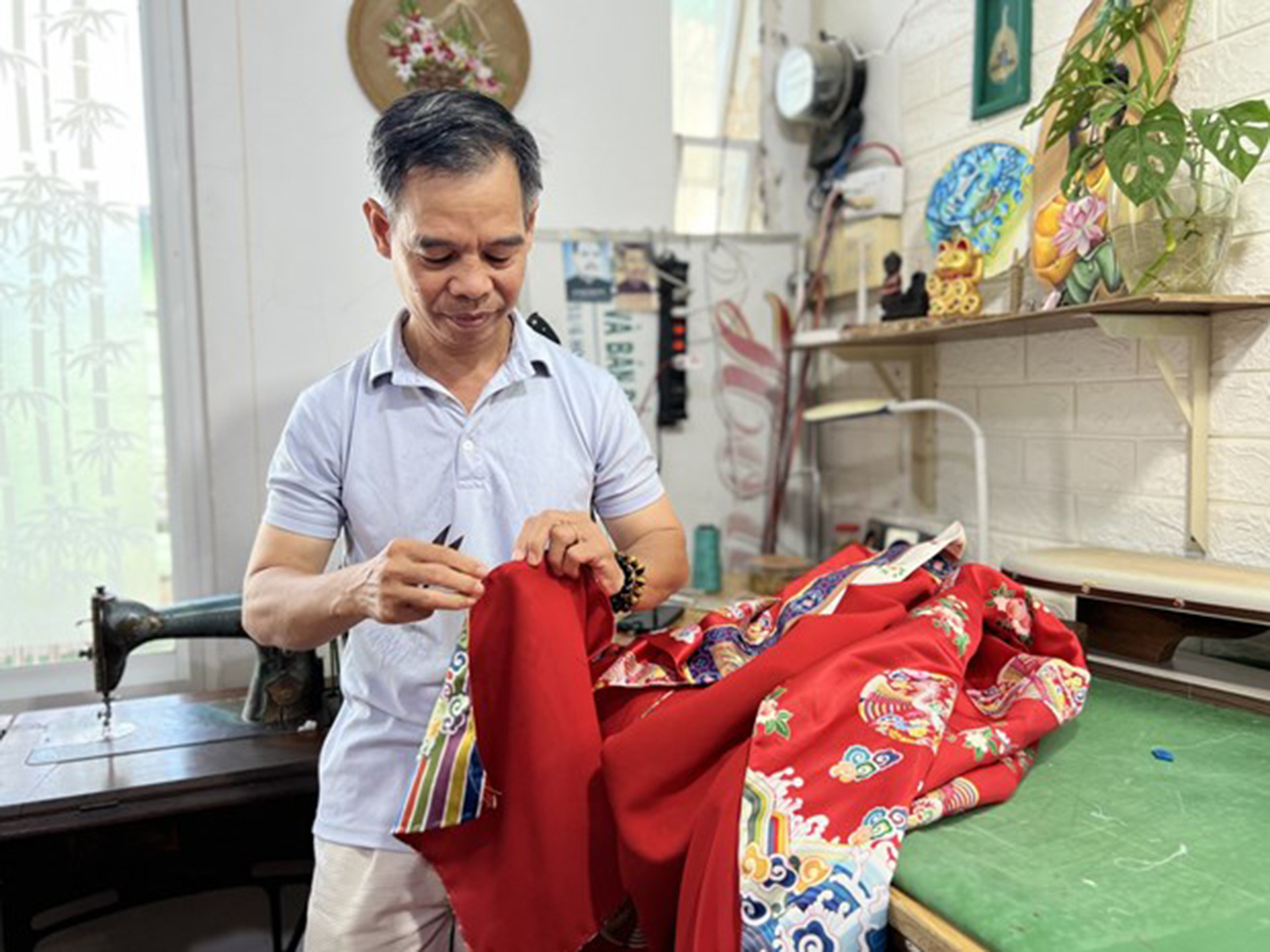 Ông Trần Thanh Tòng hoàn thiện một chiếc áo dài Nhật bình. Ảnh: Ánh Tuyết – TTXVN