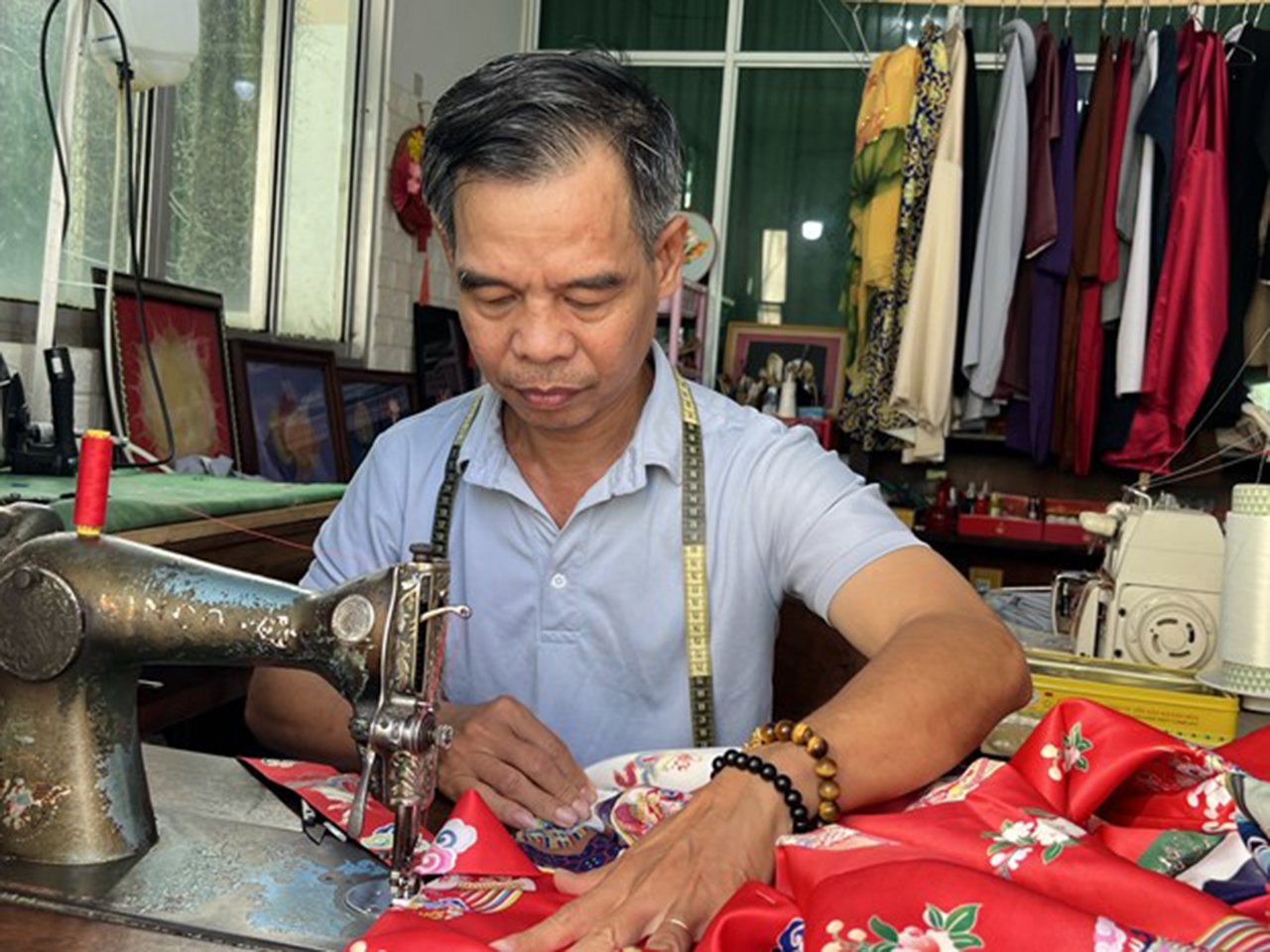 Ông Trần Thanh Tòng đang hoàn thiện chiếc áo dài cổ phục. Ảnh: Ánh Tuyết - TTXVN