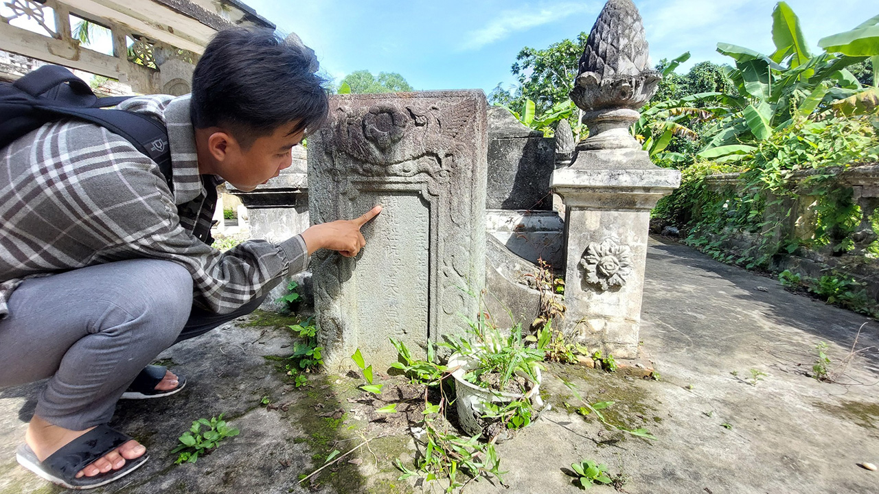 Linh nghiên cứu, đọc chữ Hán Nôm tại một ngôi mộ xưa - Ảnh Báo Thanh Niên