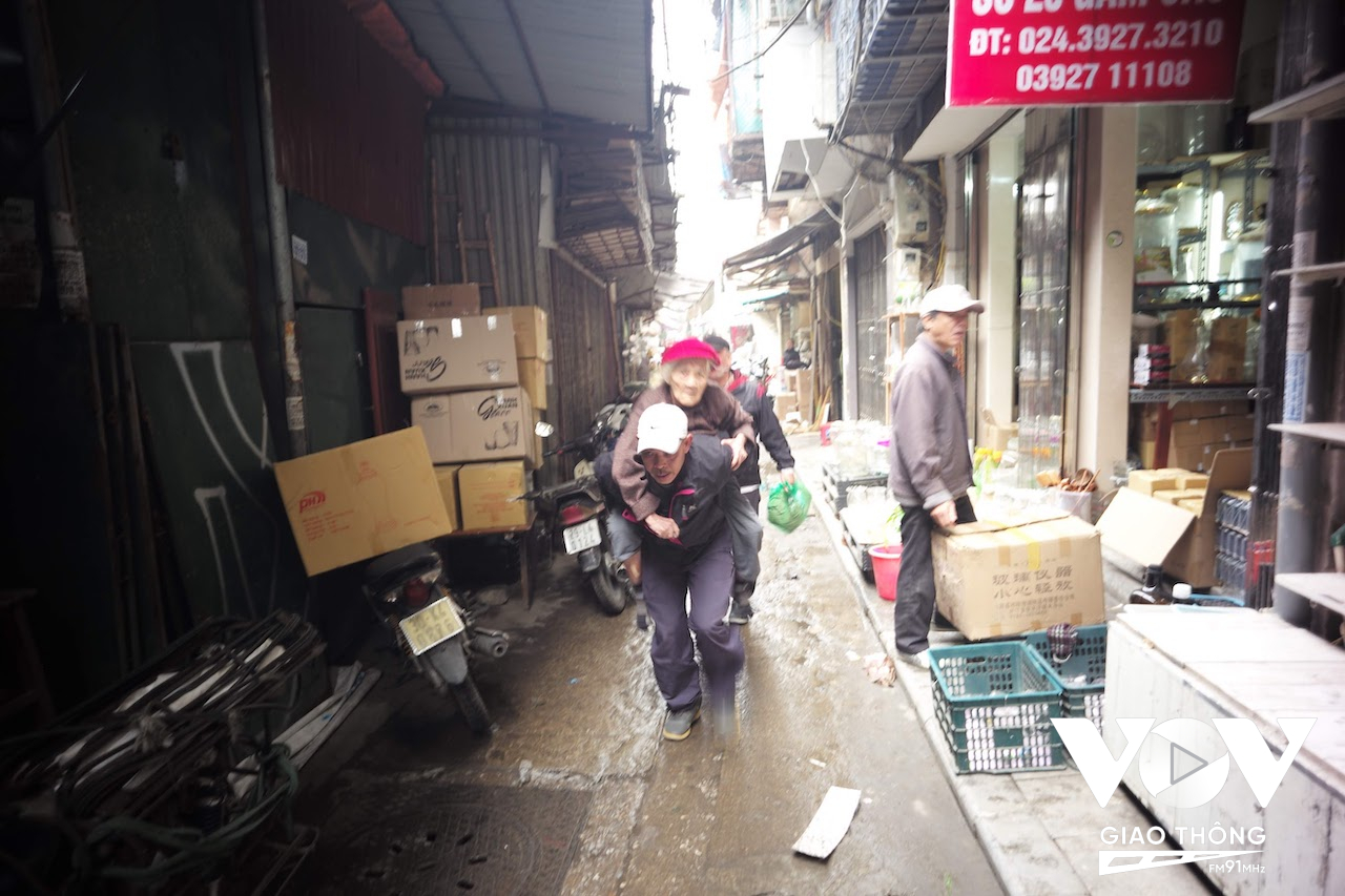 Người con trai phải cõng mẹ chạy bộ từ trong ngõ ra xe cấp cứu vì ngõ hẹp xe không thể vào tới nơi trên phố Gầm Cầu, Hoàn Kiếm, Hà Nội