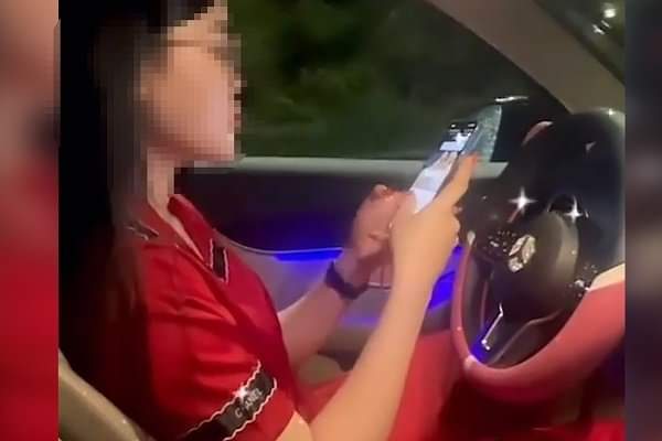 Nữ tài xế điều khiển xe ô tô mang nhãn hiệu Mercedes dán mắt vào điện thoại để quay Tiktok