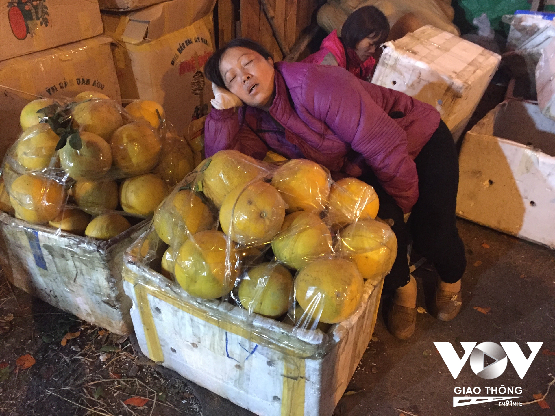 Một người phụ nữ ngủ vùi ngay bên những sọt hàng giữa chợ Long Biên. Công việc của họ tưởng chừng như kéo dài bất tận, từ sáng ngày hôm trước, xuyên đêm cho tới sáng ngày hôm sau