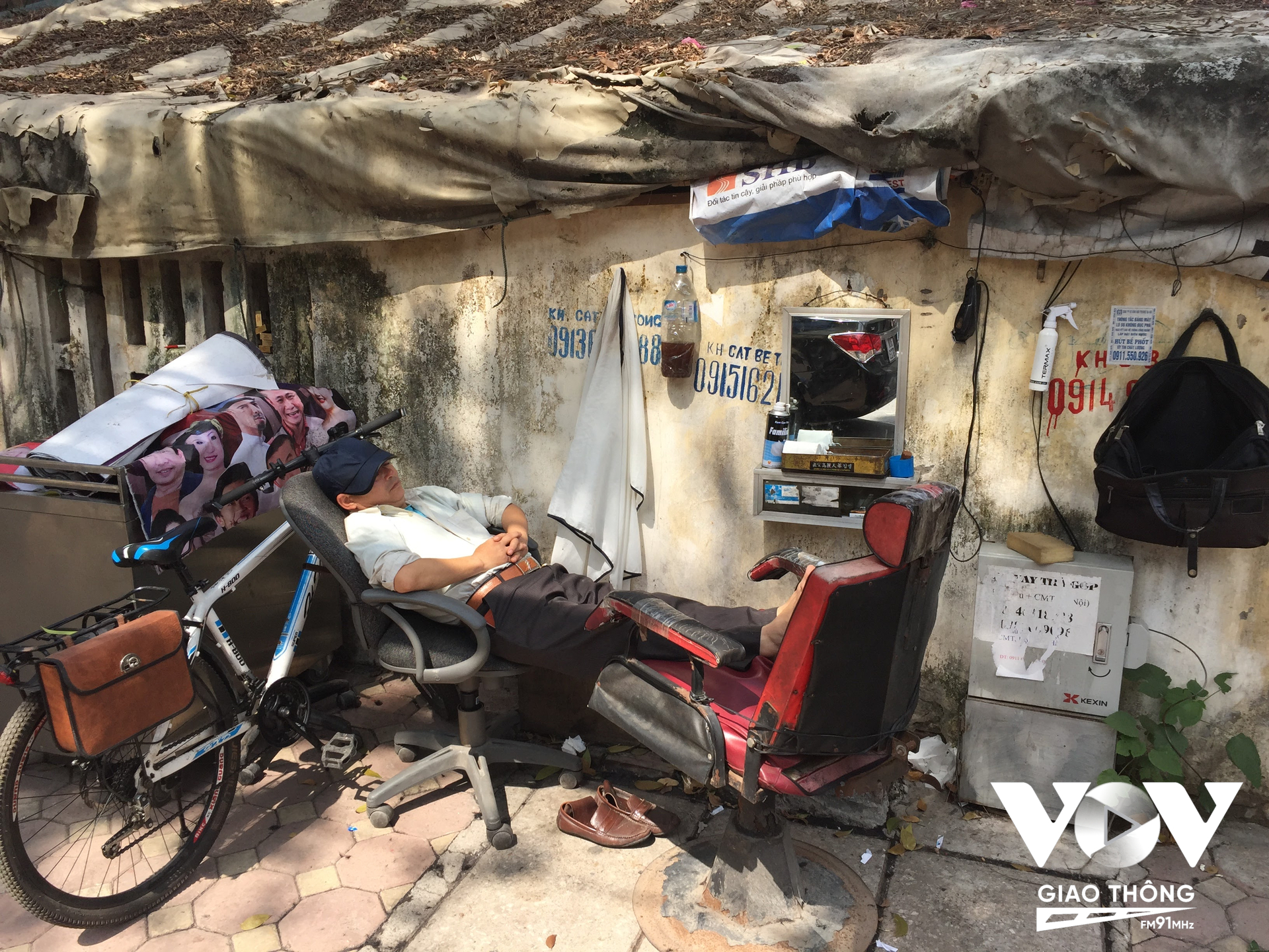 Một người thợ cắt tóc trên vỉa hè phố Nguyễn Du nằm nghỉ khi vắng khách