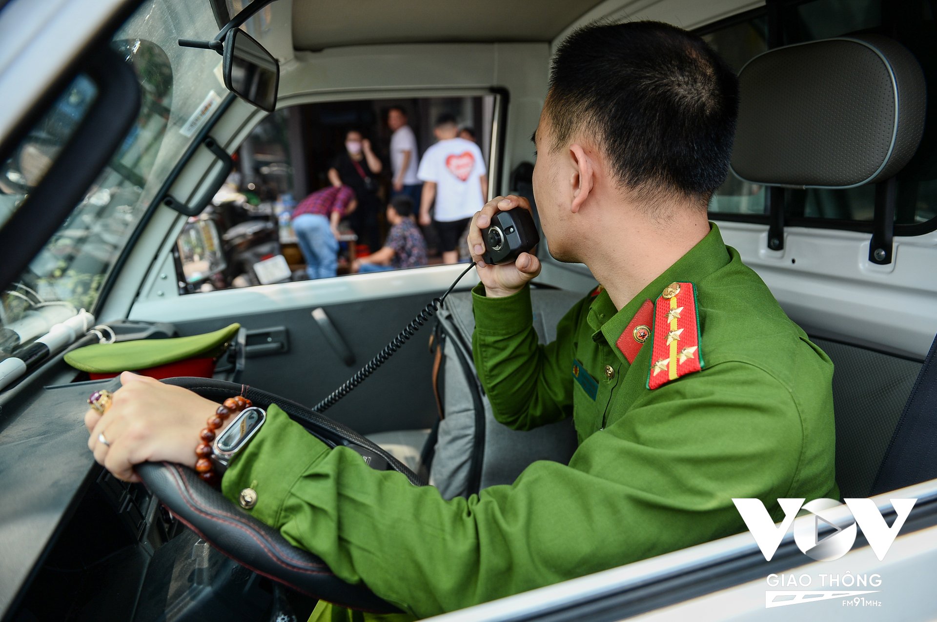 Lực lượng công an phường Thượng Đình, quận Thanh Xuân (Hà Nội) đọc loa nhắc nhở các hộ kinh doanh thu dọn bàn ghế lấn chiếm vỉa hè.