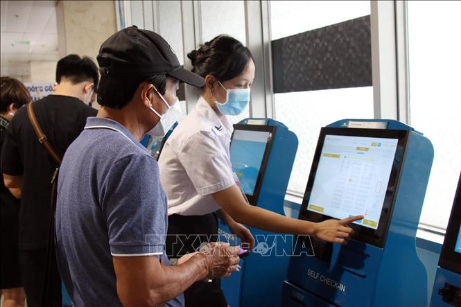 Nhân viên tại sân bay Tân Sơn Nhất hỗ trợ hành khách làm thủ tục tại các trụ check-in. Ảnh: Tiến Lực/TTXVN
